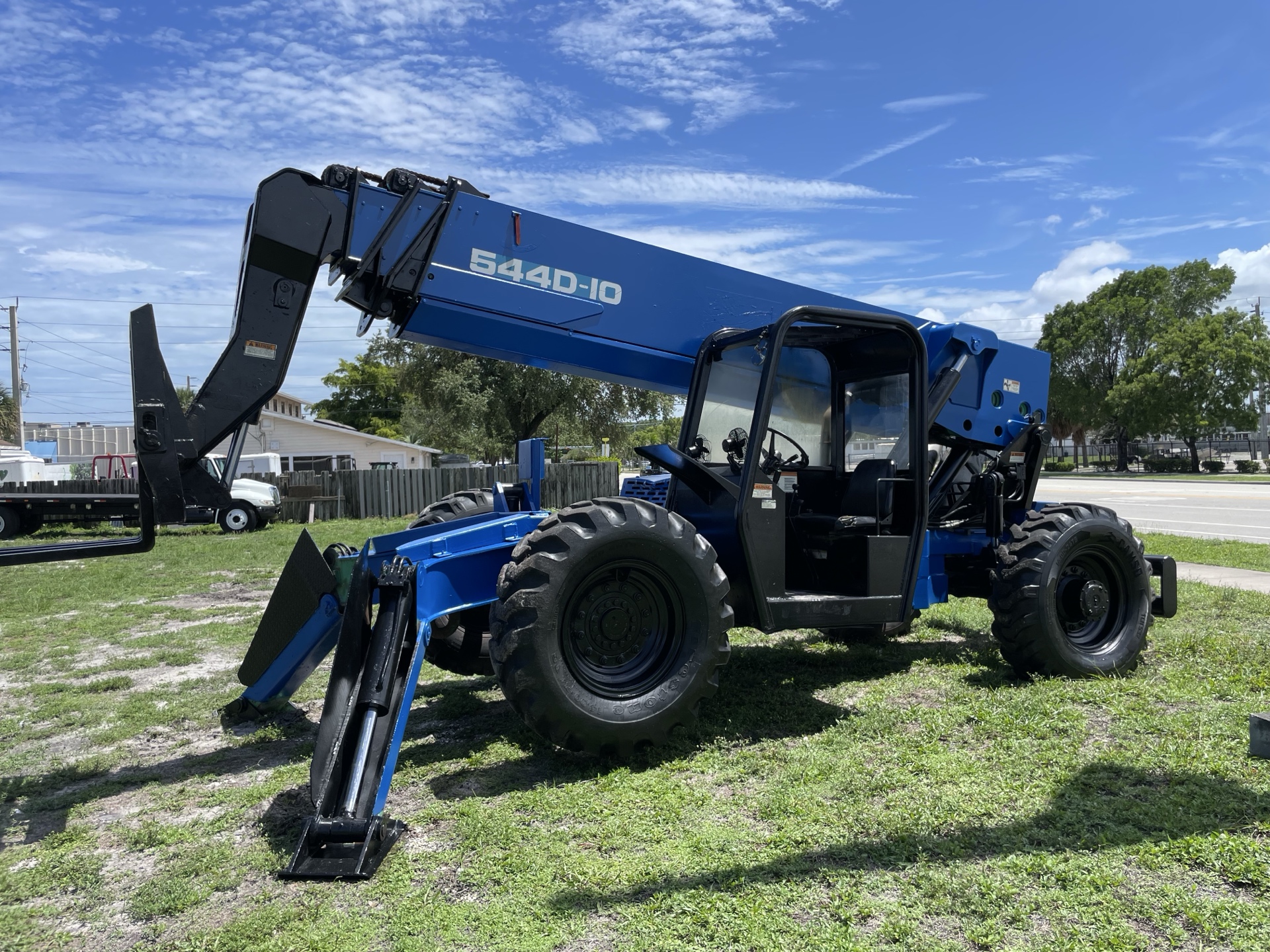Blue telehandler on a grassy jobsite