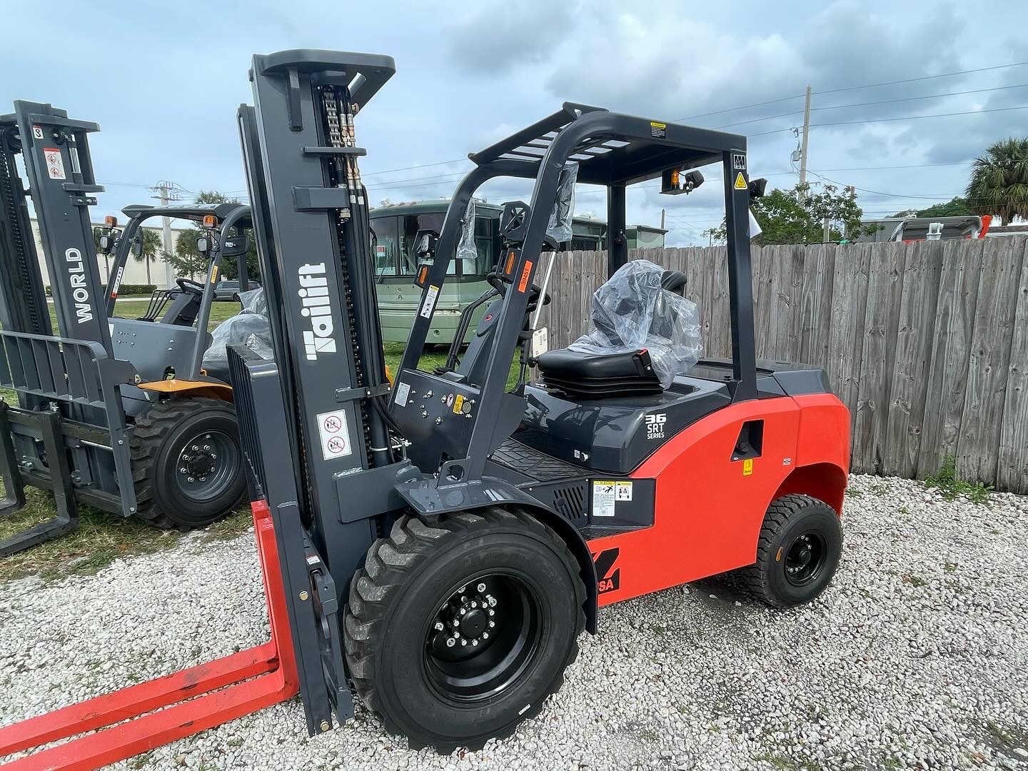 Red and gray Tailift forklift on a gravel lot